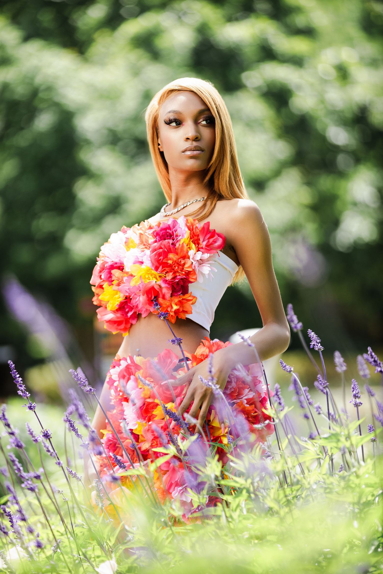 Fashion portrait in natural setting with coral floral dress and blooming lavender.
