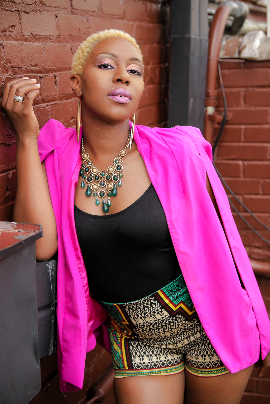 Fashion portraits featuring hot pink blazer and statement necklace against brick wall background.