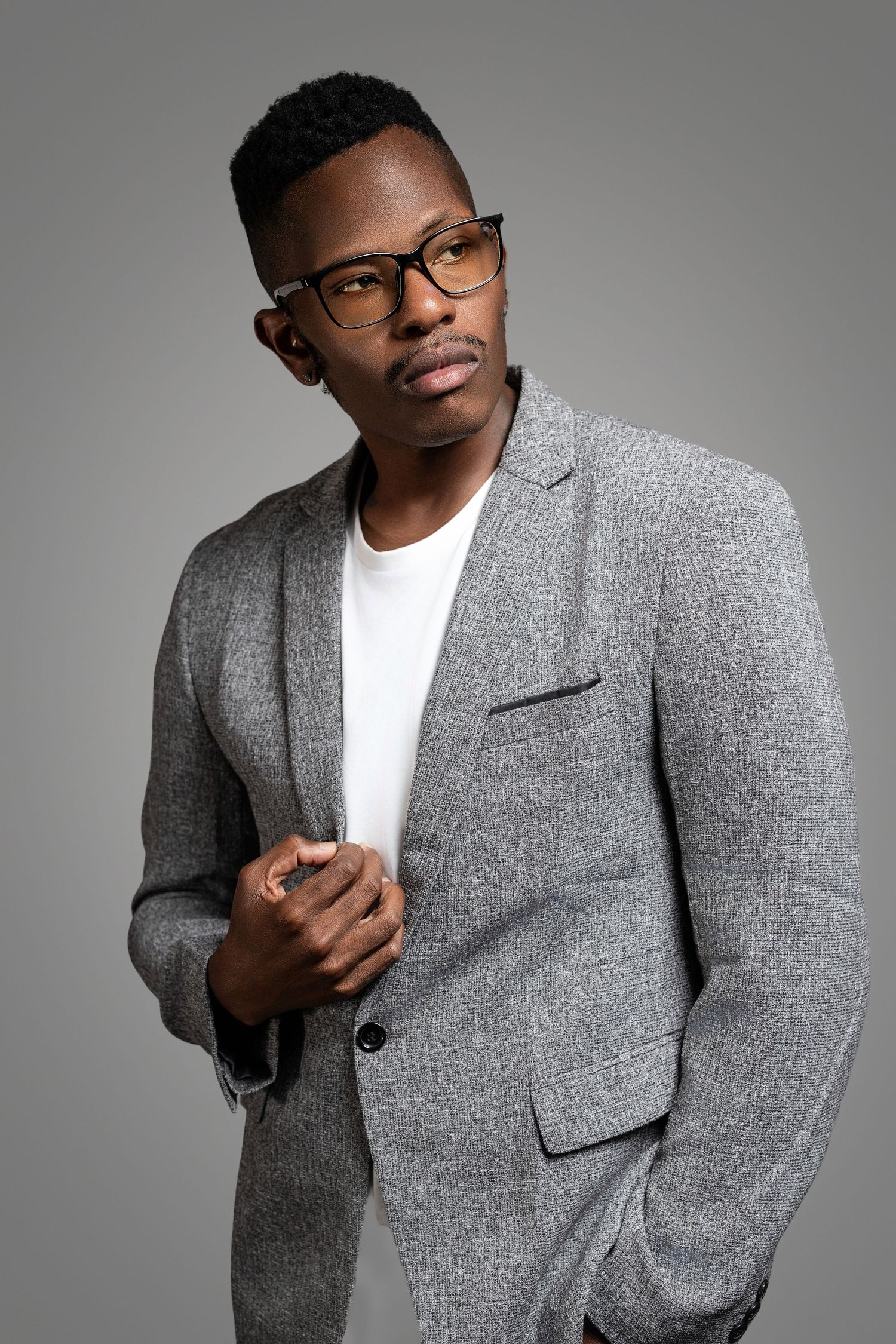 Professional modeling shots featuring grey blazer and glasses in studio setting.