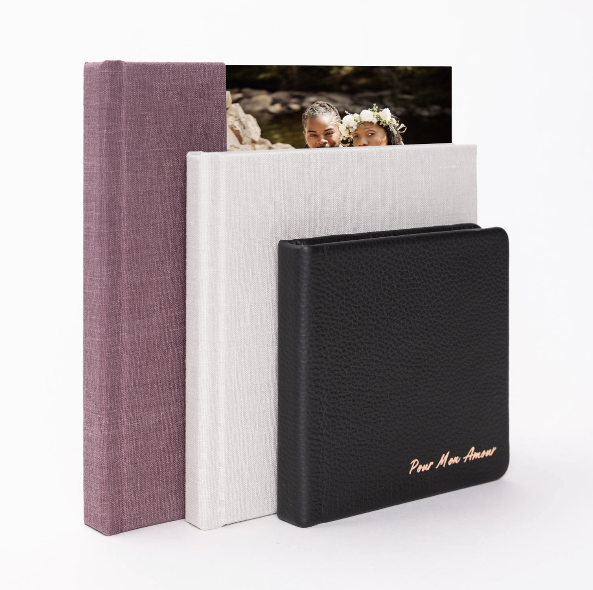 Three elegant photo album boxes in black, white, and mauve colors arranged to showcase their minimalist design.
