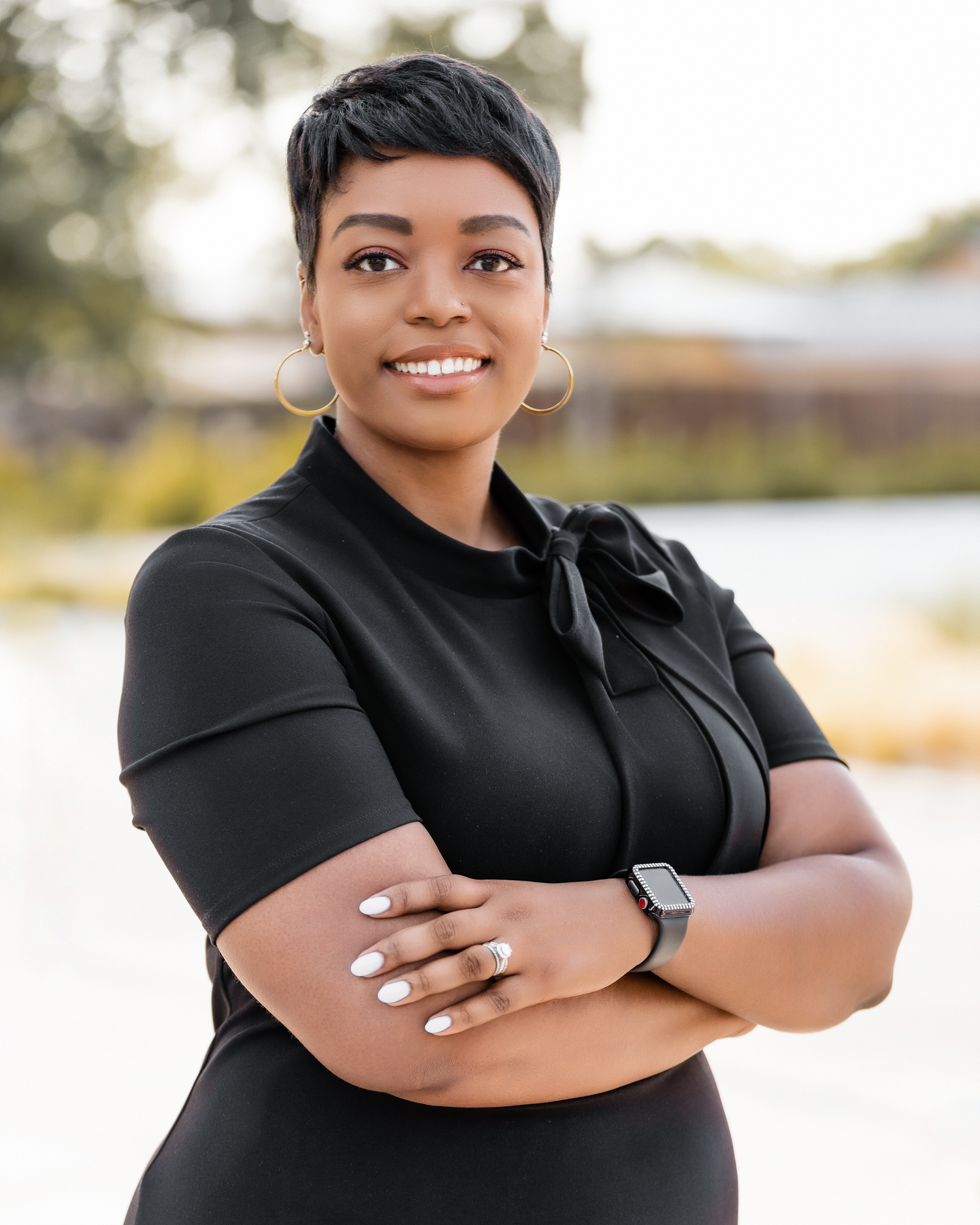 Professional outdoor portrait in black outfit with smartwatch and short hairstyle.