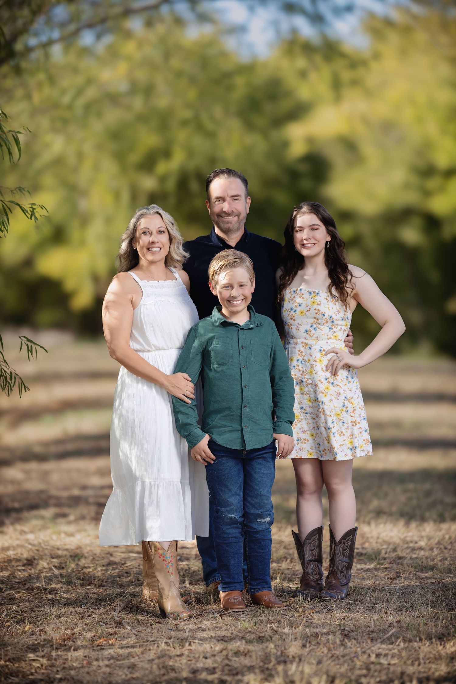 Natural light family portrait session among trees with coordinated casual outfits.