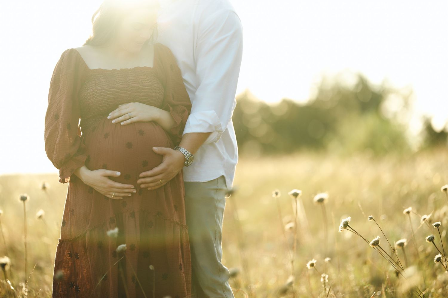 Romantic sunset photoshoot in a field with soft golden lighting.