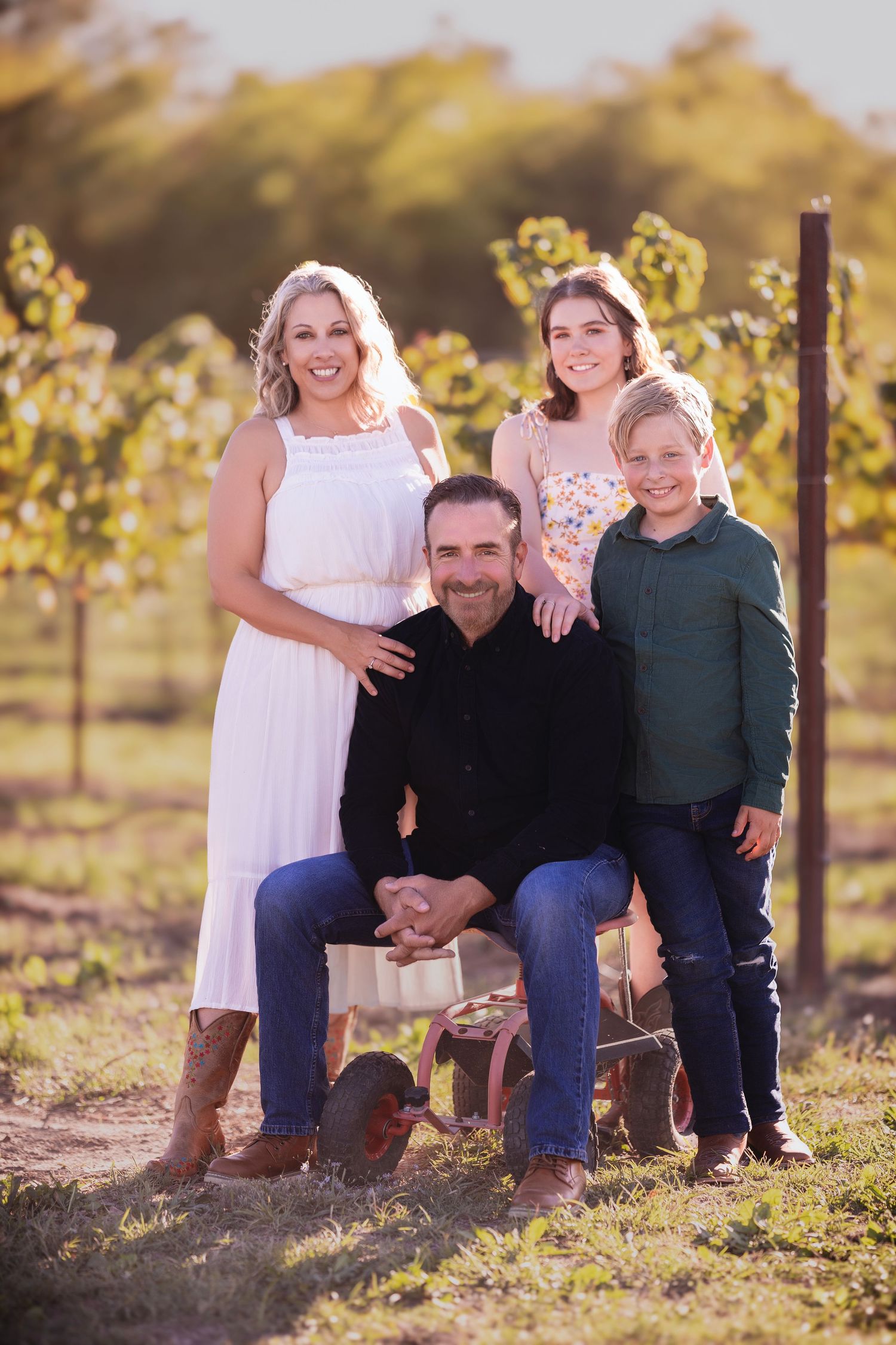Casual family photos taken at sunset in a vineyard setting with wooden posts.