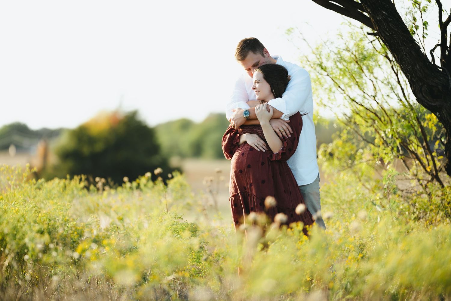 Romantic outdoor photoshoot in a sunlit field with natural greenery.