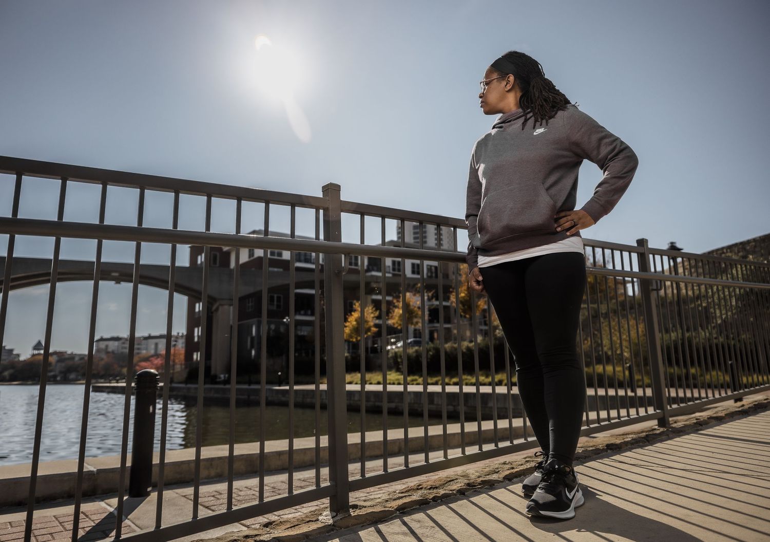 Person stretching and exercising on a wooden boardwalk by the water during sunset.