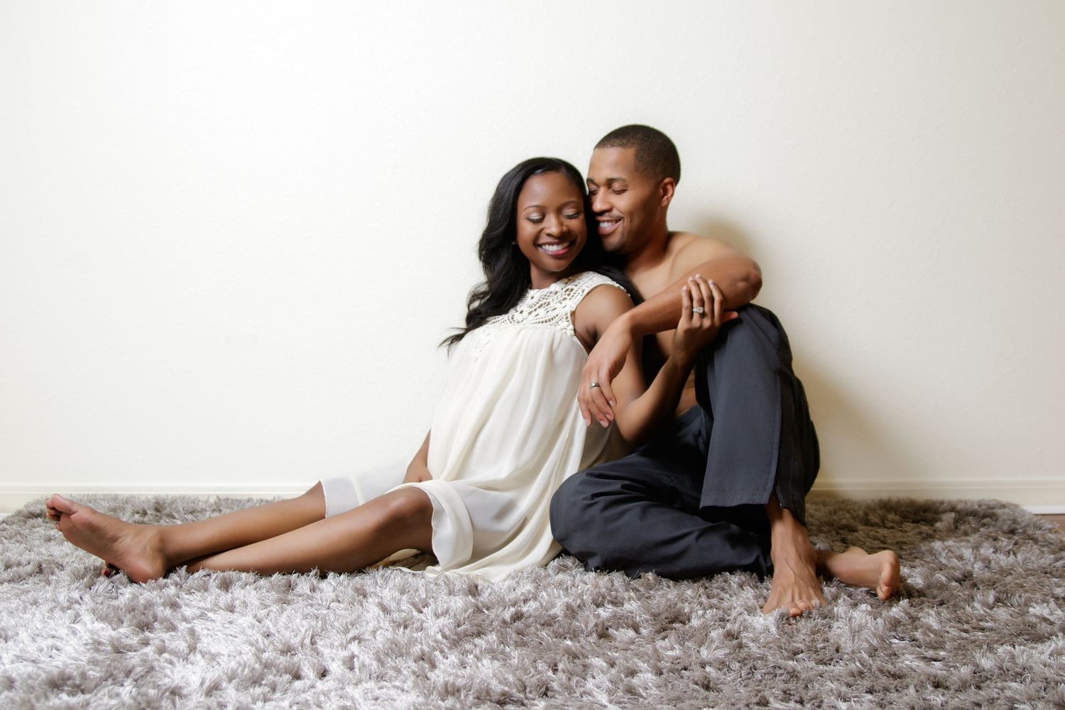 Couple sharing an intimate moment while sitting on a plush gray carpet.