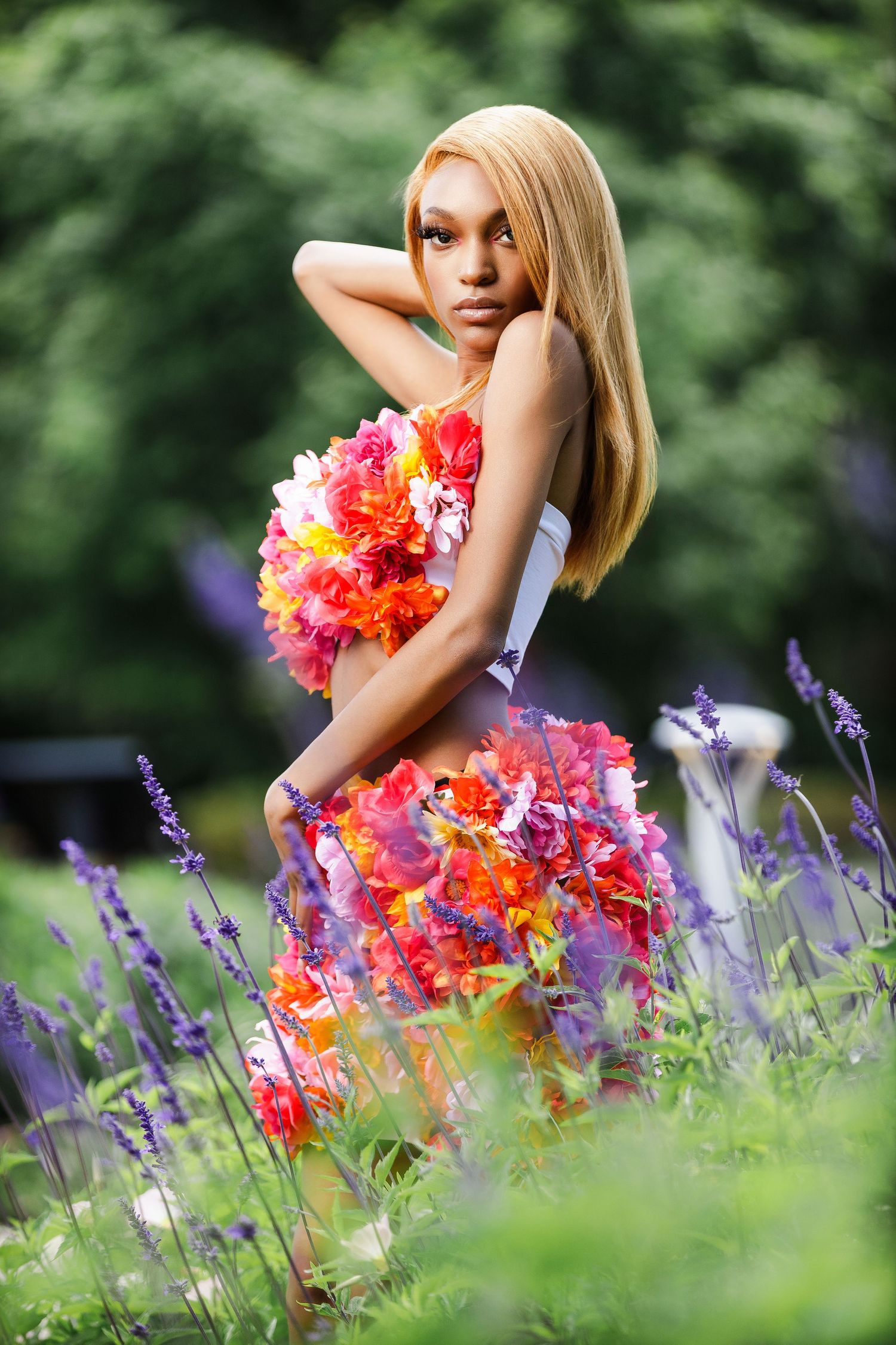 Summer fashion photography in garden setting with coral flowers and purple lavender.