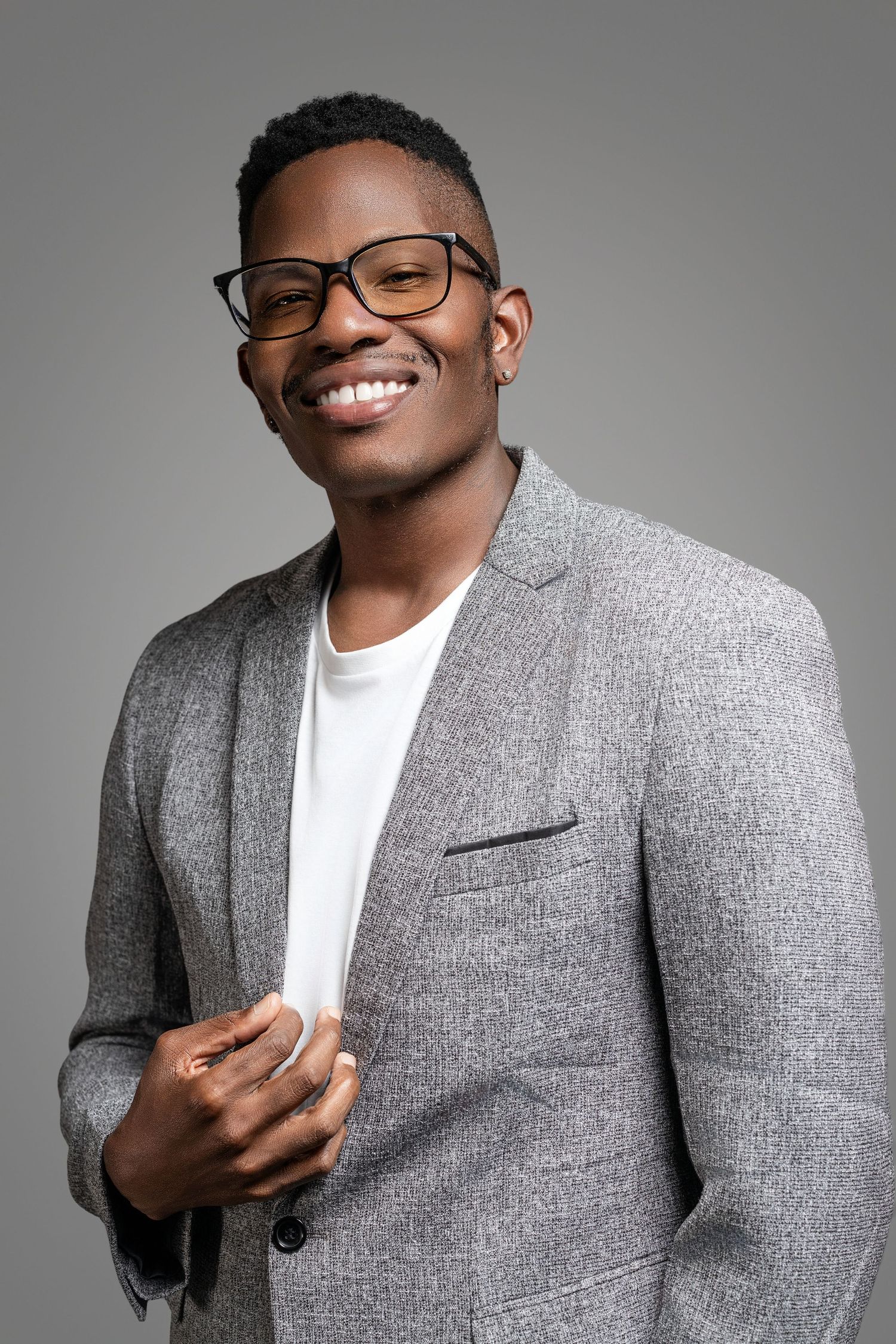 Studio portrait series in grey blazer and white t-shirt against neutral background.