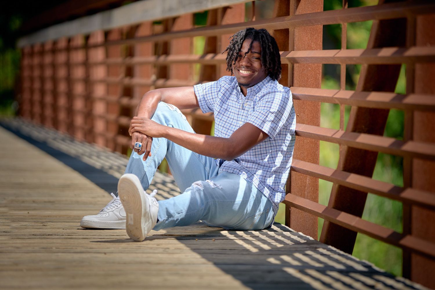Casual outdoor portraits on wooden bridge featuring relaxed poses in natural lighting.