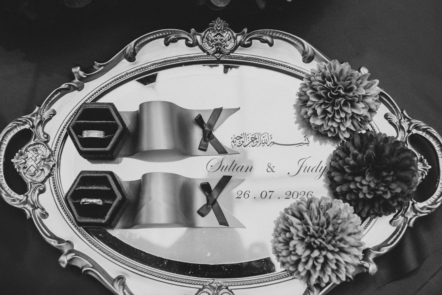 Black and white photo of bespoke elegant wedding rings on ornate silver tray with floral decor