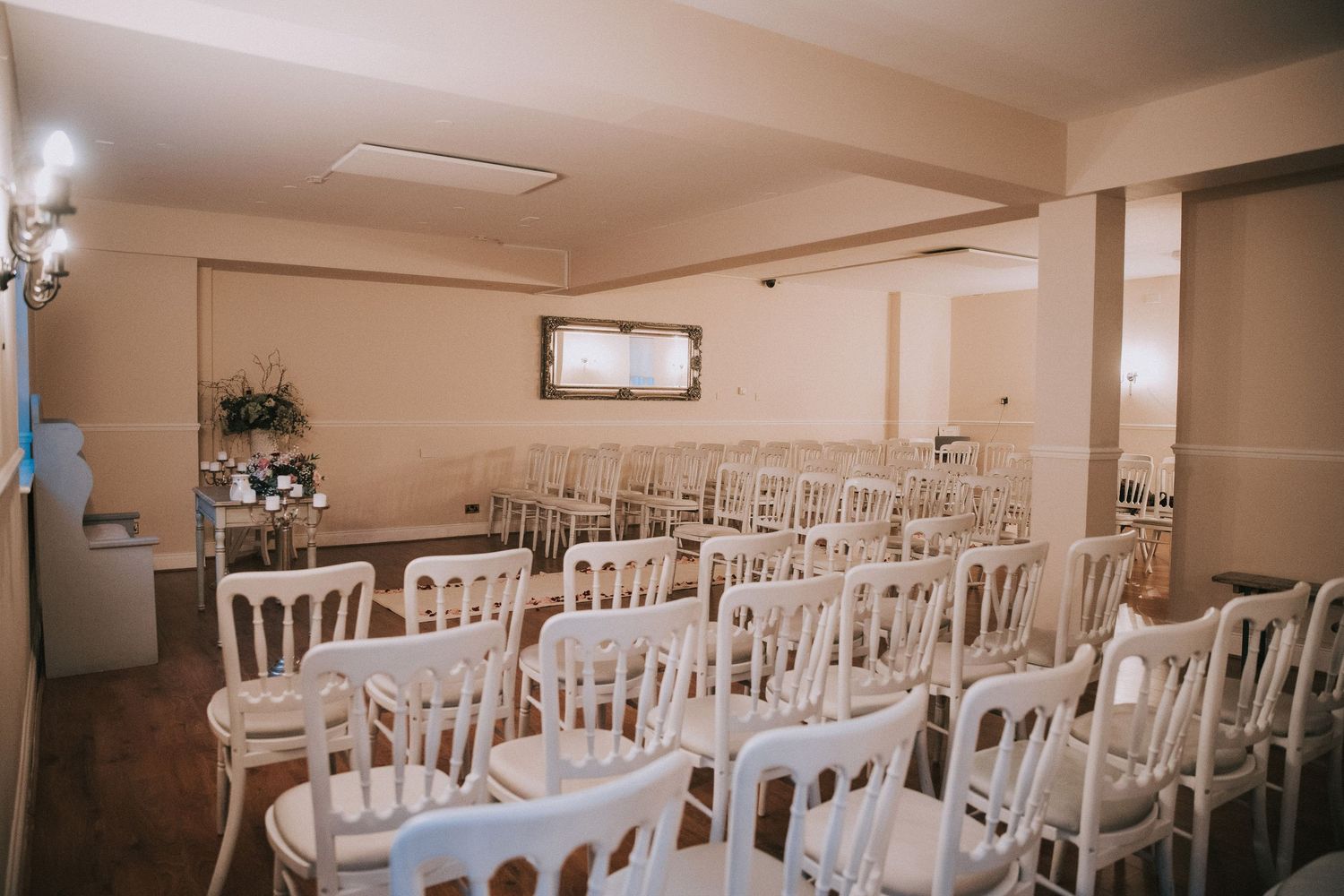 Elegant wedding ceremony room with rows of white Chiavari chairs arranged for guests in a softly lit venue.