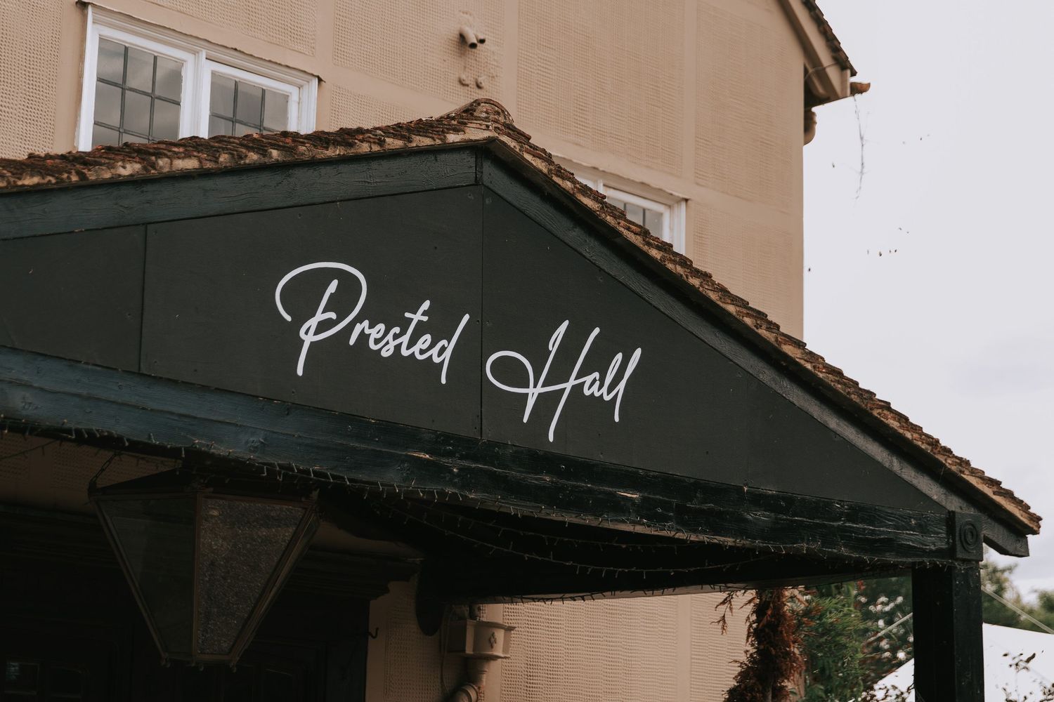 Prested Hall venue entrance with elegant dark green awning and white cursive signage.