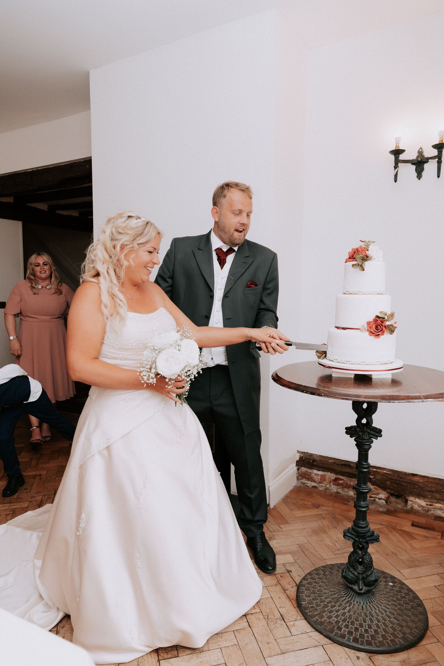 Bride and groom cutting their white two-tier wedding cake together at their elegant indoor wedding reception.