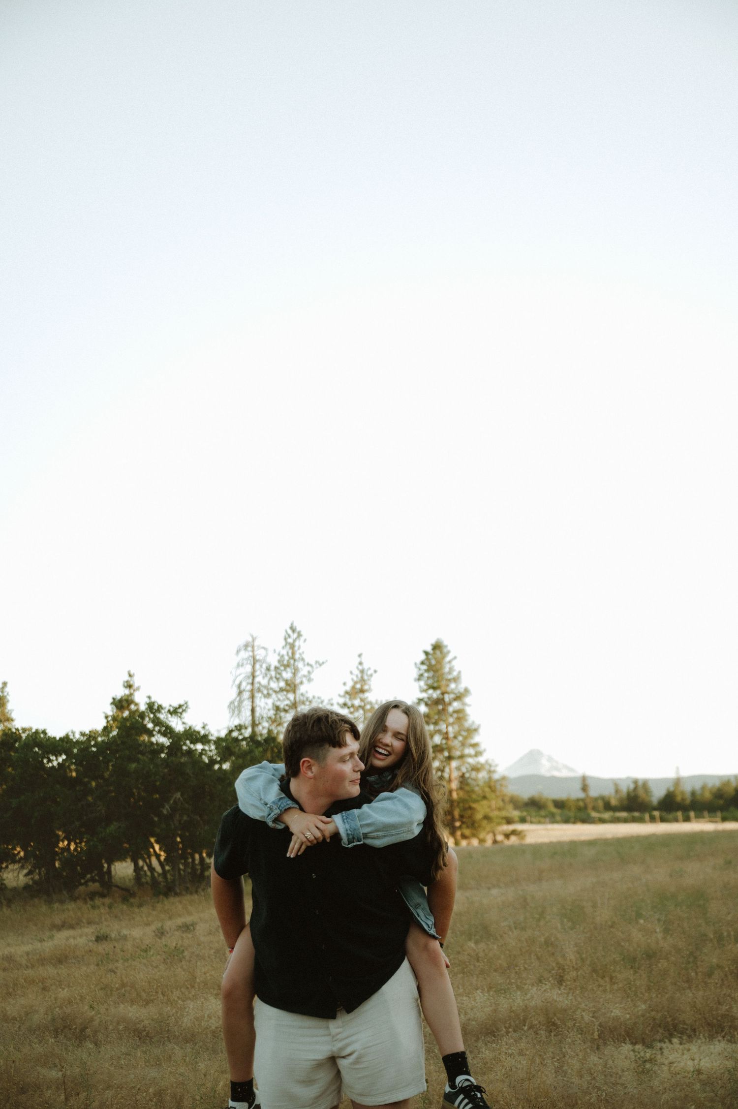 Couple embracing in a scenic field during golden hour.