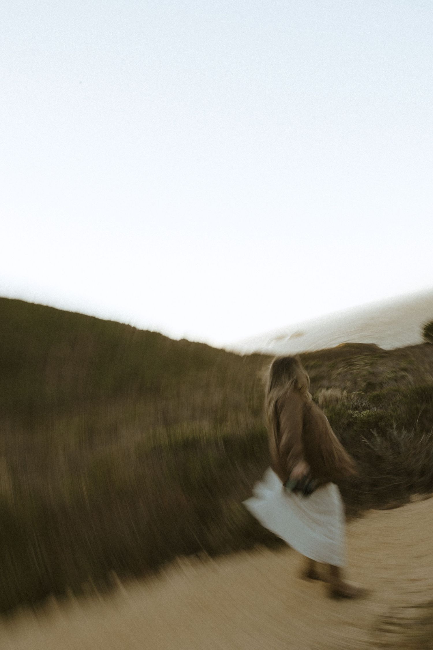 Artistic motion blur photograph of someone moving across a hillside landscape.