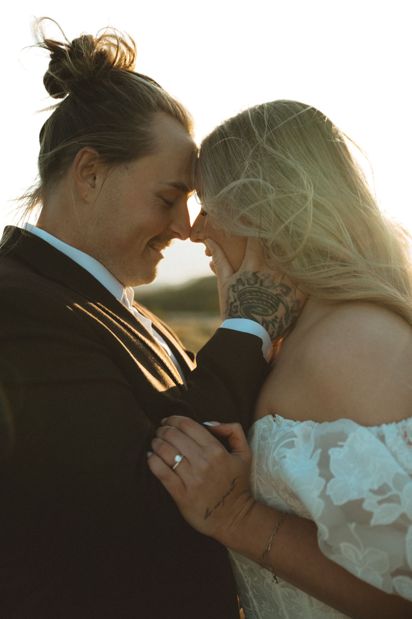 Intimate sunset moment between newlyweds with soft golden lighting.