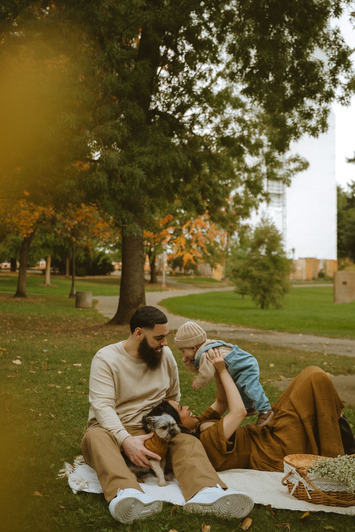 Couple relaxing on a blanket under autumn trees in a park setting.