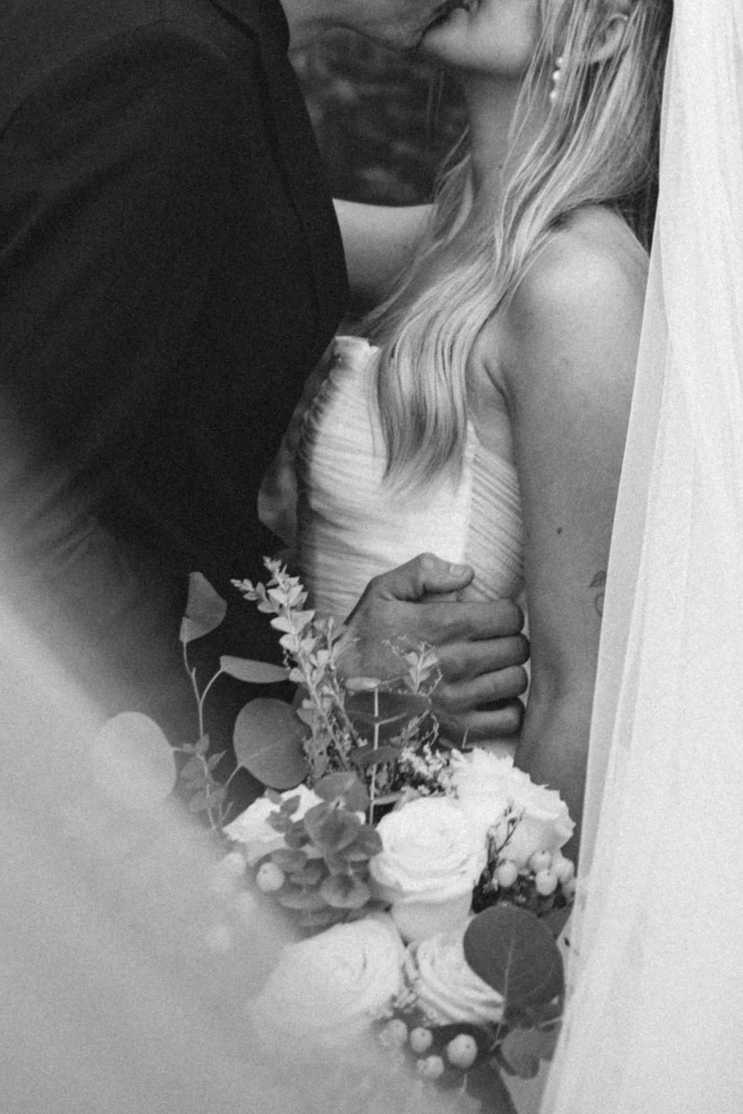 Black and white portrait showing wedding dress details and bouquet.
