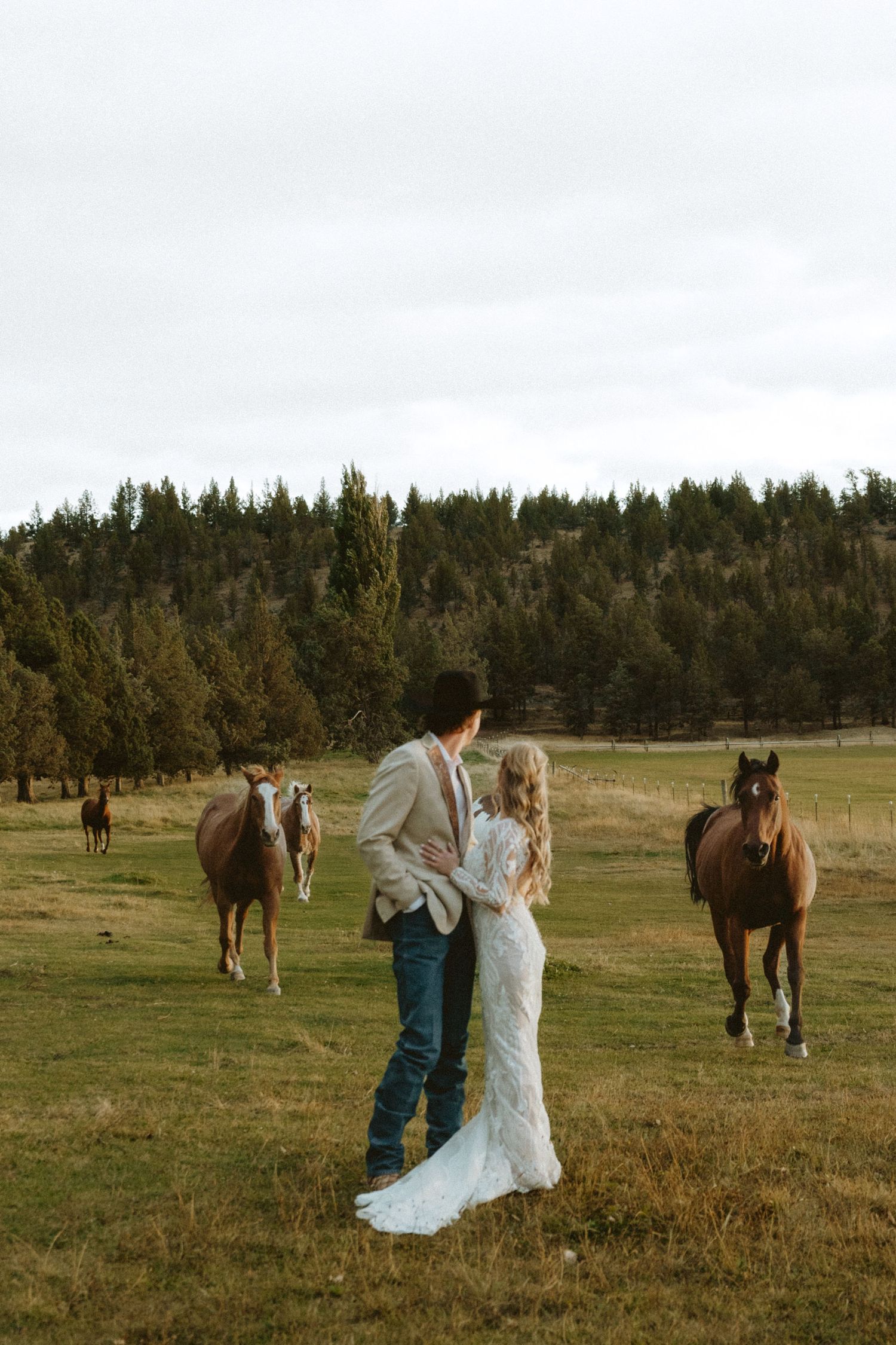 Candid western wedding photo of a couple with horses in Sisters, Oregon, captured in a timeless documentary style.