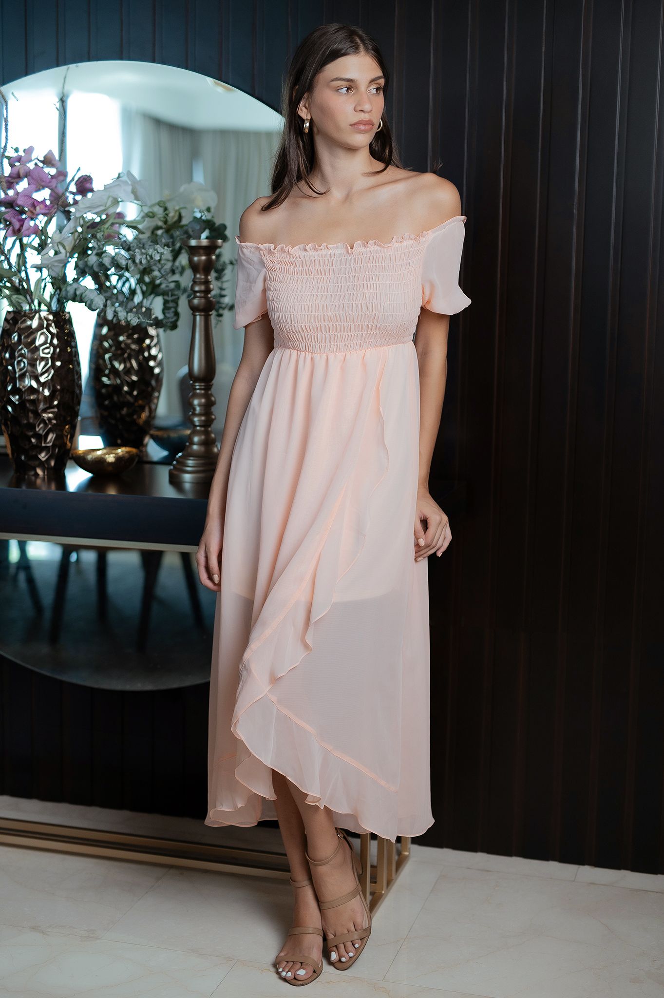 Woman in elegant off-shoulder peach maxi dress posing in front of a mirror.