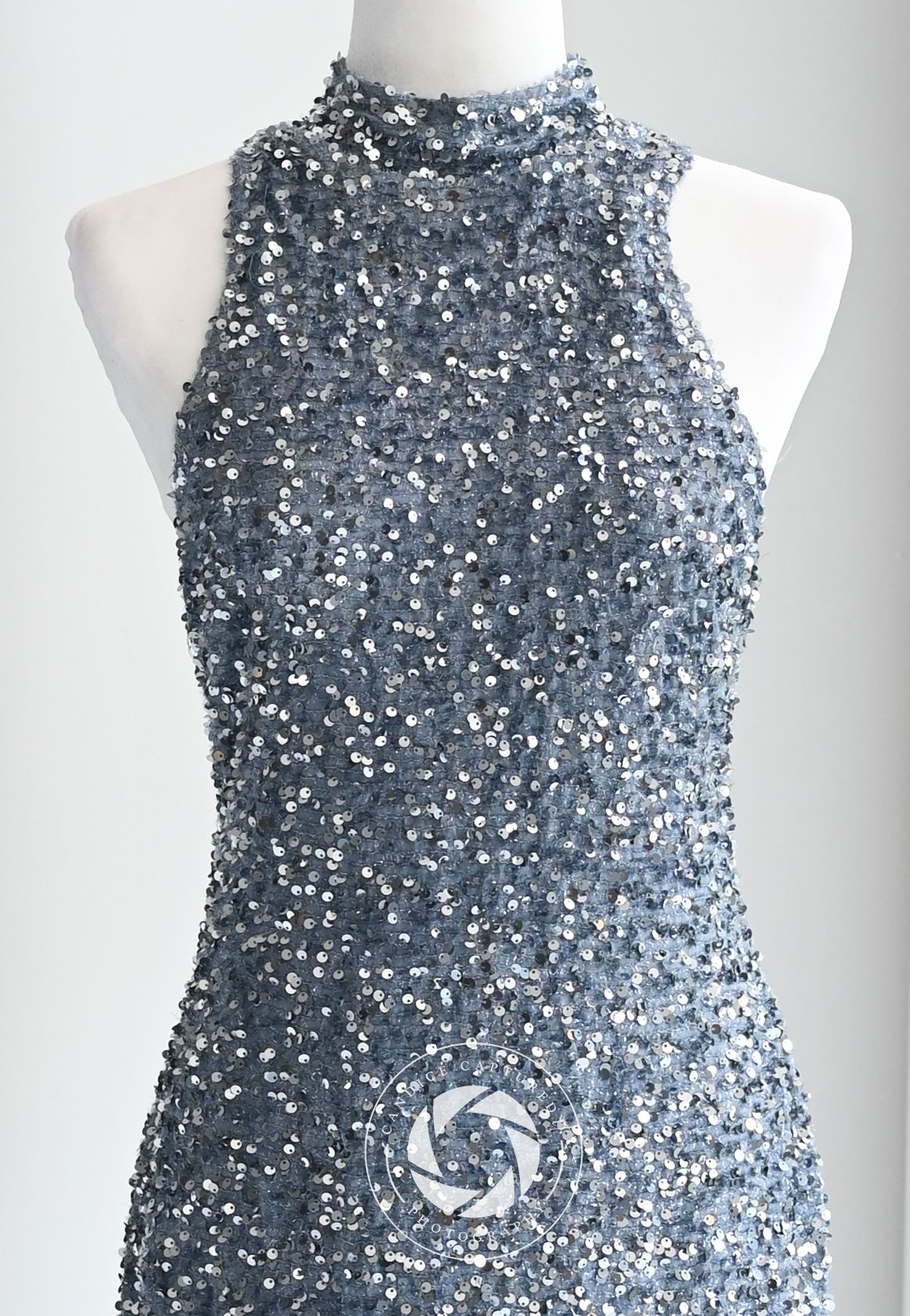 A stunning silver sequined cocktail dress displayed on a white mannequin with a high neckline and sleeveless design.