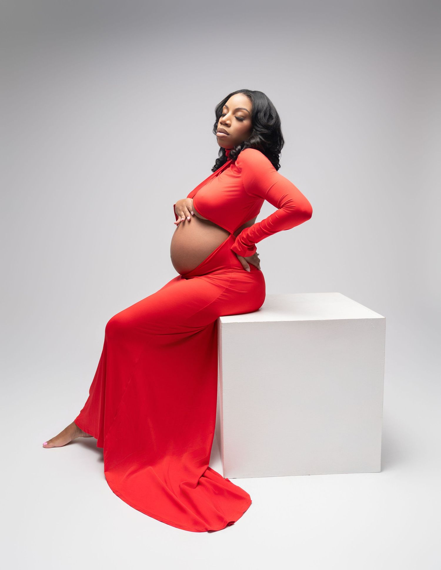 Plus size model in flowing red dress poses elegantly against white backdrop in dynamic fashion photoshoot series.