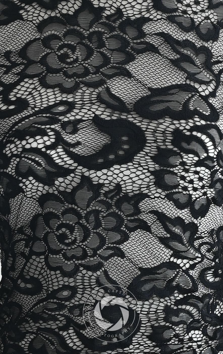Close-up detail of black floral lace fabric showing delicate patterns and textures in monochromatic tones.