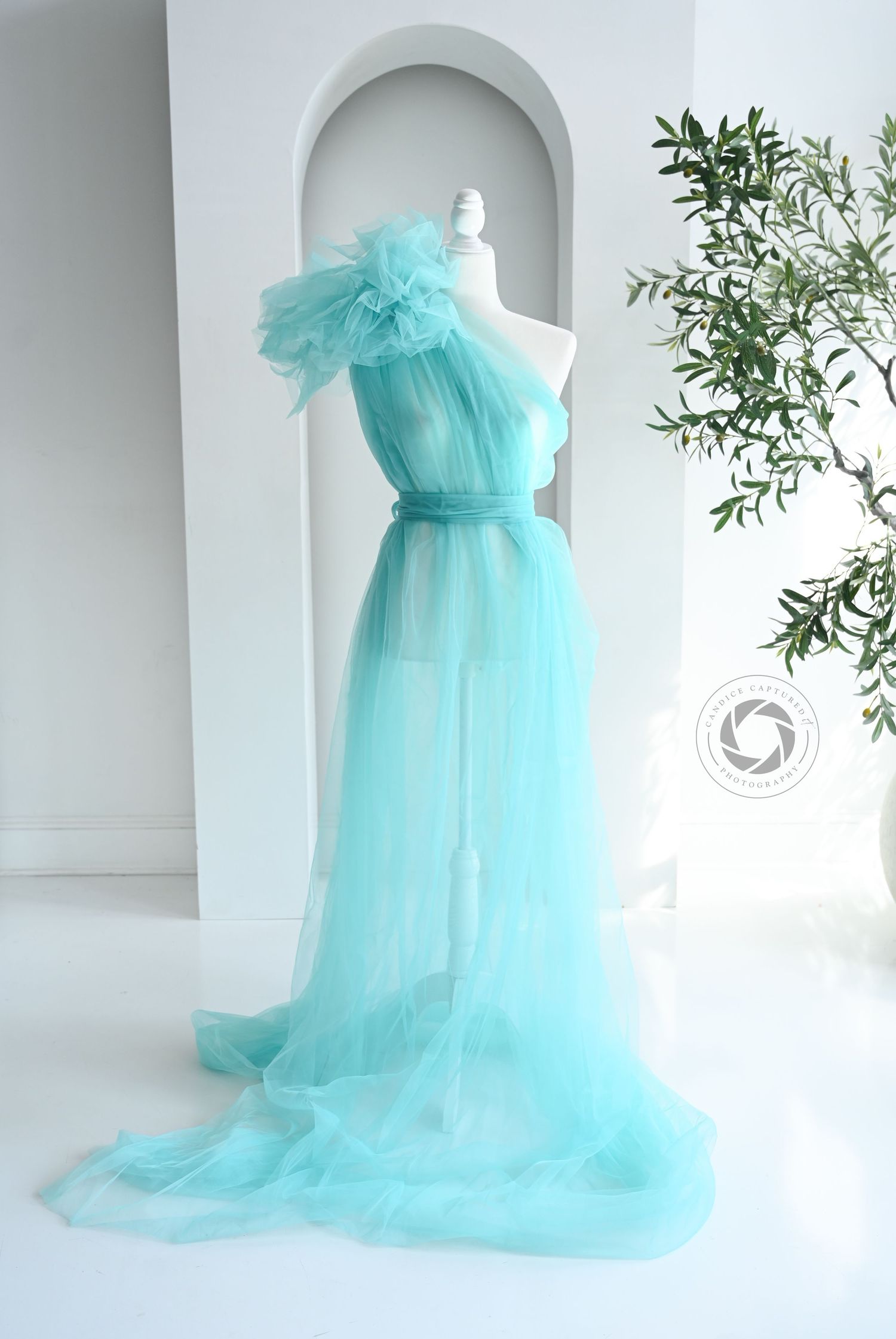 Ethereal turquoise tulle maternity dress showcased in multiple angles against a white studio backdrop with green foliage.