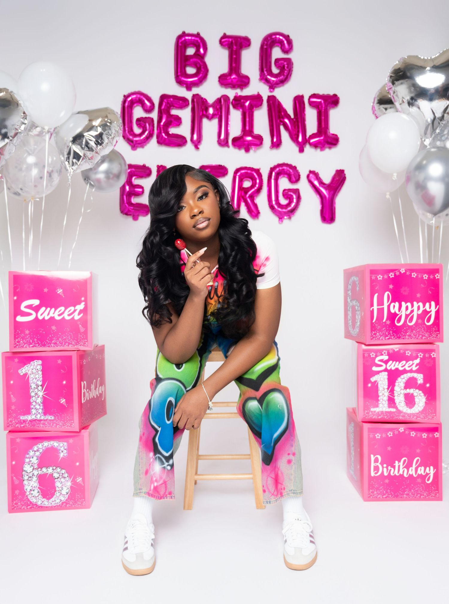 Sweet 16 birthday party decorations in pink with balloons and gift boxes arranged in a festive display.