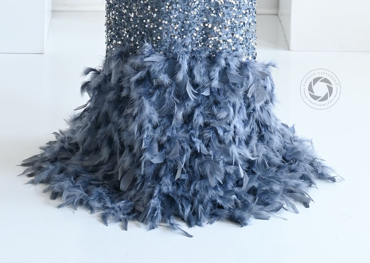 A billowing, cascading ruffle of steel blue tulle fabric creates dramatic texture and movement on a white background.