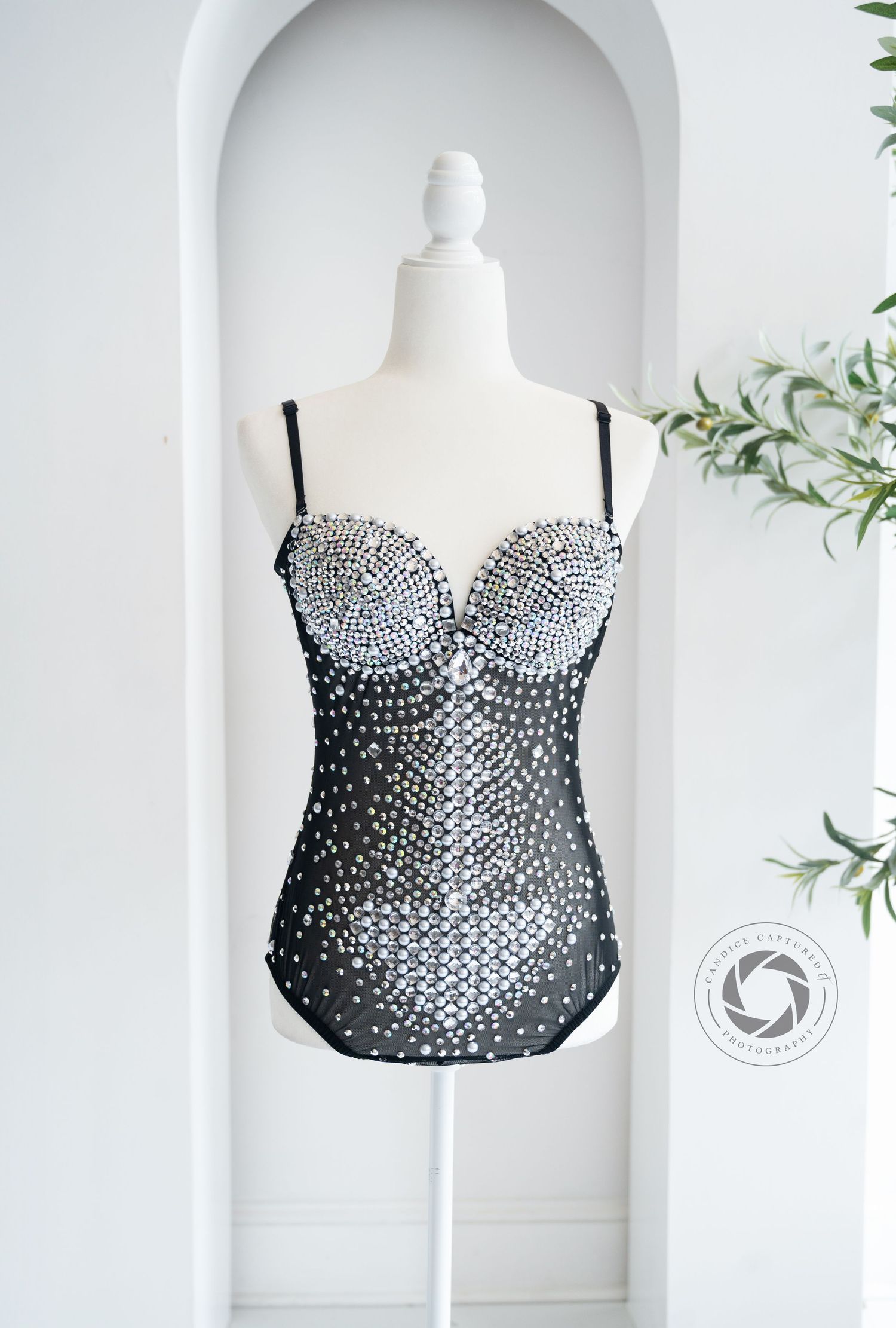 Black strapless corset top with silver rhinestone embellishments displayed on white mannequin form.