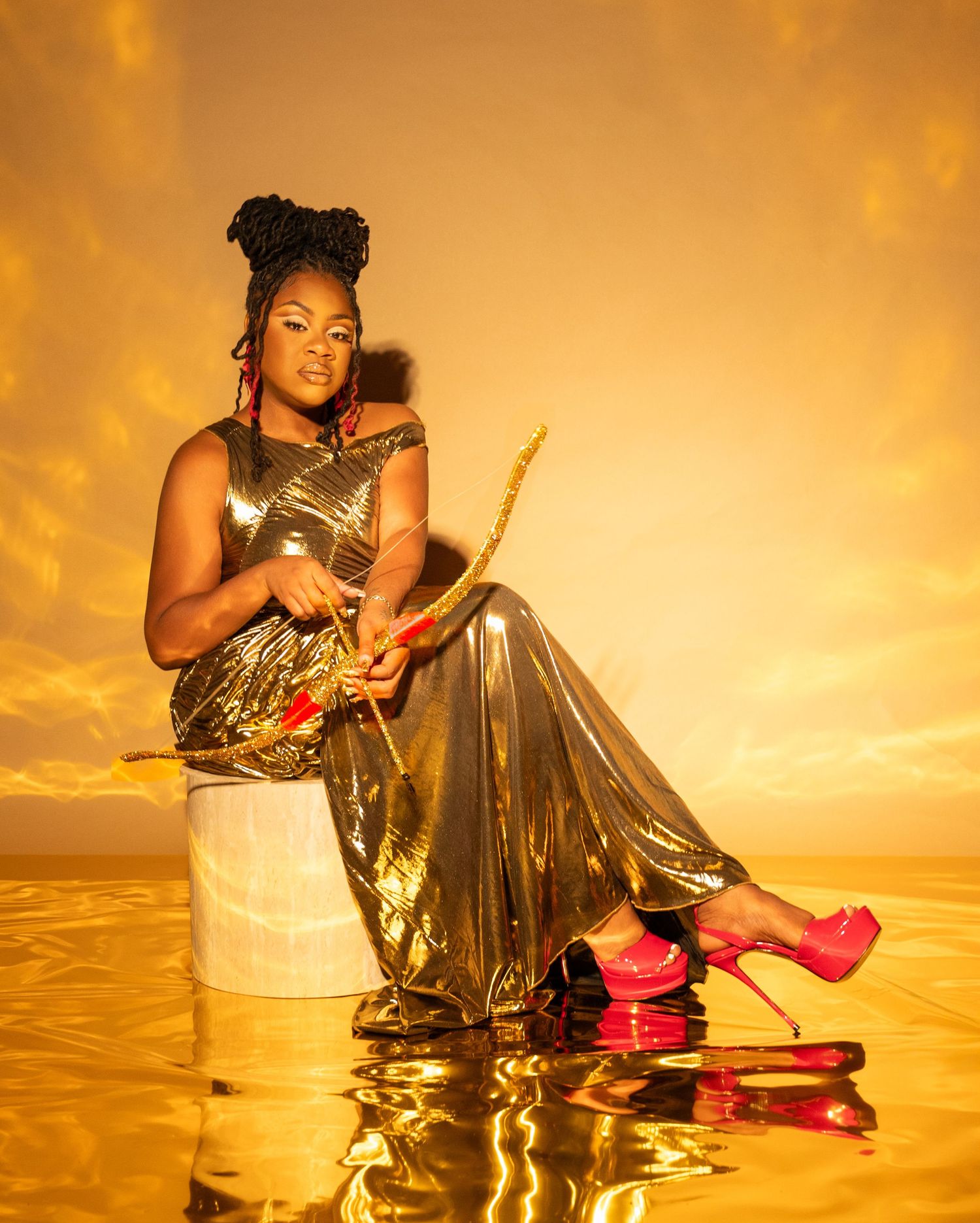 A figure in a gold metallic dress and red roller skates poses against a warm sunset backdrop in an artistic photoshoot.