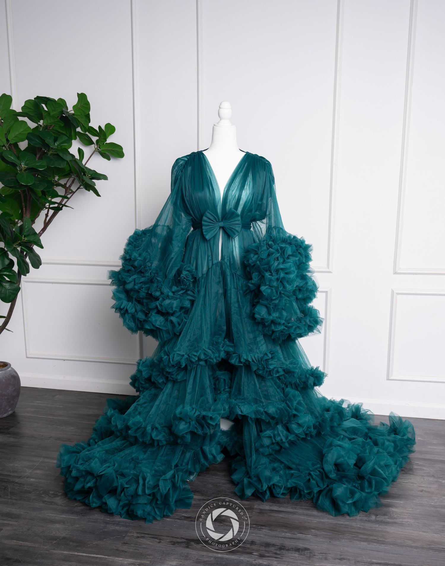 Luxurious emerald green tulle robe with dramatic ruffled sleeves and flowing tiered skirt displayed on mannequin.