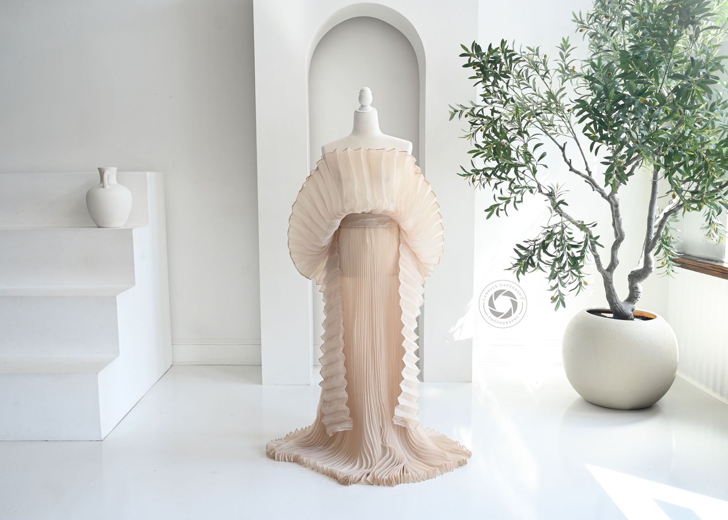 A dreamy white and beige interior design with a minimalist vase, plant, and draped fabric creating an elegant aesthetic.
