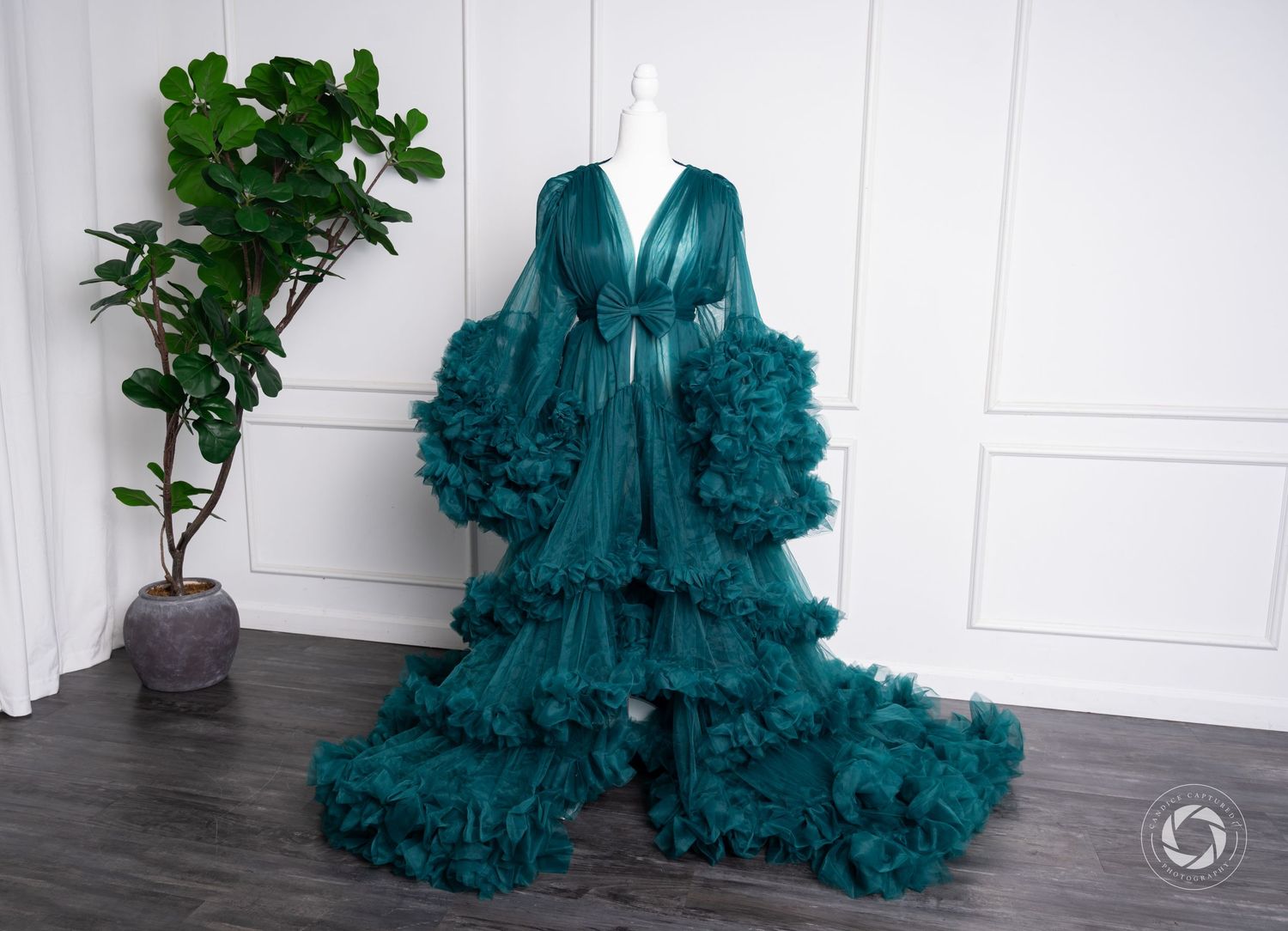 Luxurious emerald green ruffled sheer robe with dramatic tiered tulle detail and long bell sleeves stands displayed on mannequin.