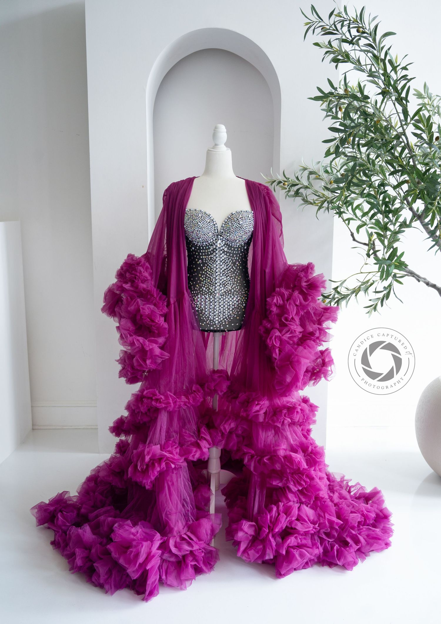 Glamorous magenta tulle robe with dramatic ruffles paired with silver sequined bodice on mannequin display.