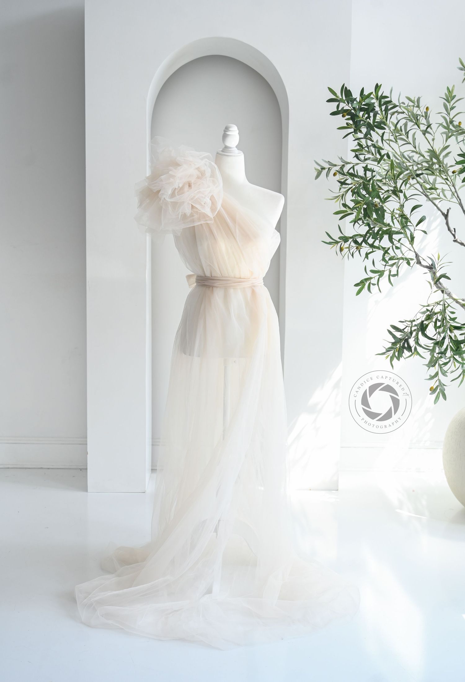 Ethereal white tulle dress photographed in sequence against a light backdrop with delicate green foliage accents.