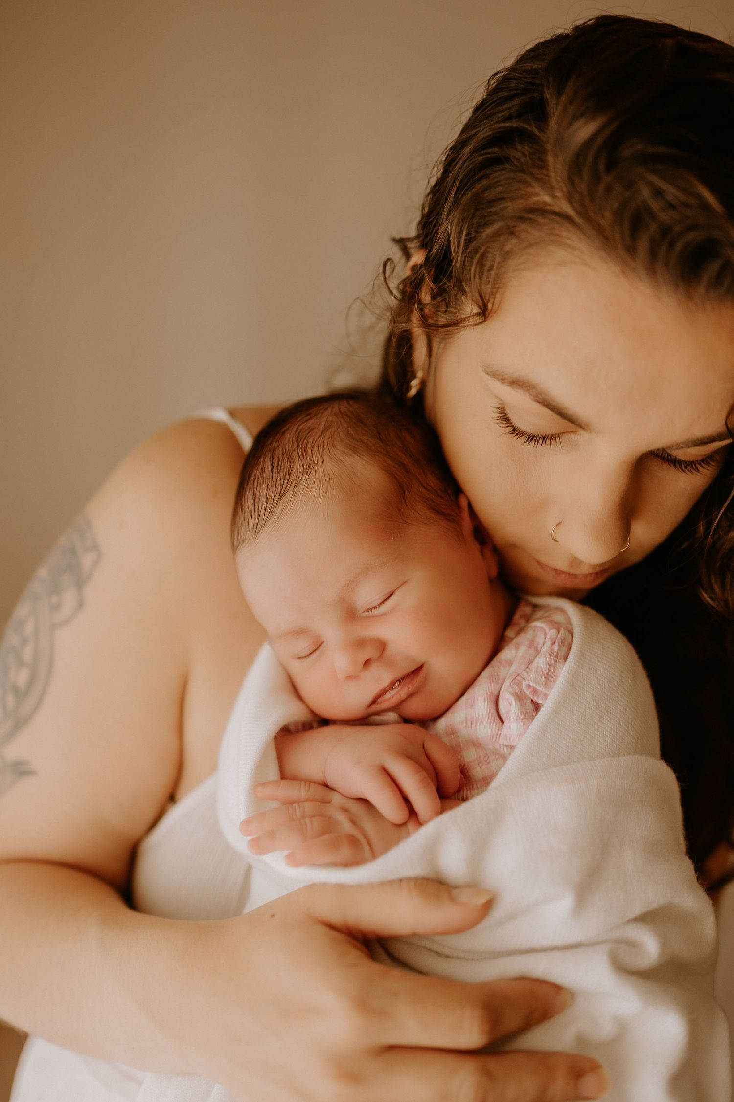 A tranquil moment captured as parent and newborn share an intimate embrace in warm, natural lighting.