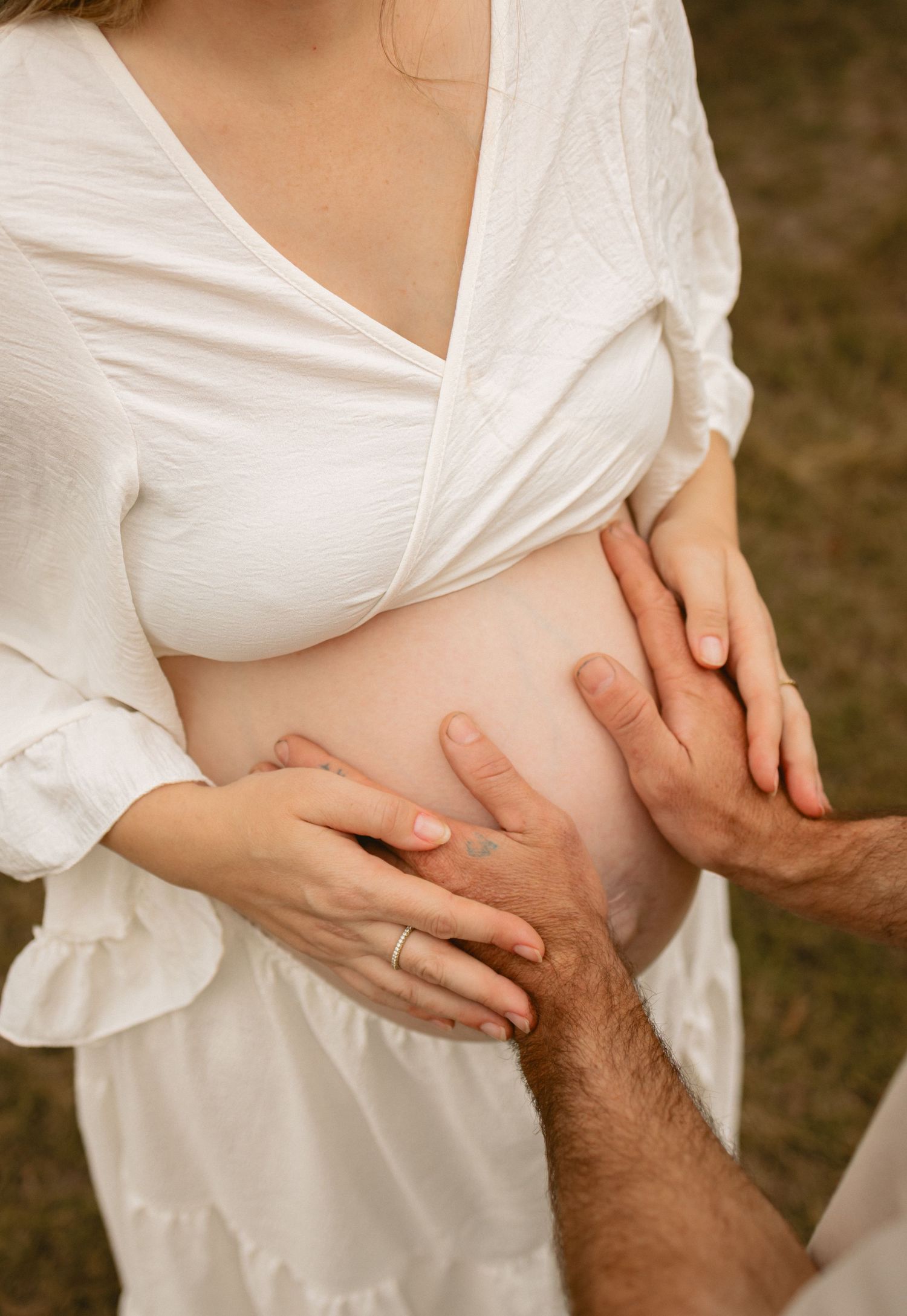 A series of connected images showing hands gently cradling a pregnant belly in a white maternity dress against a dark background.