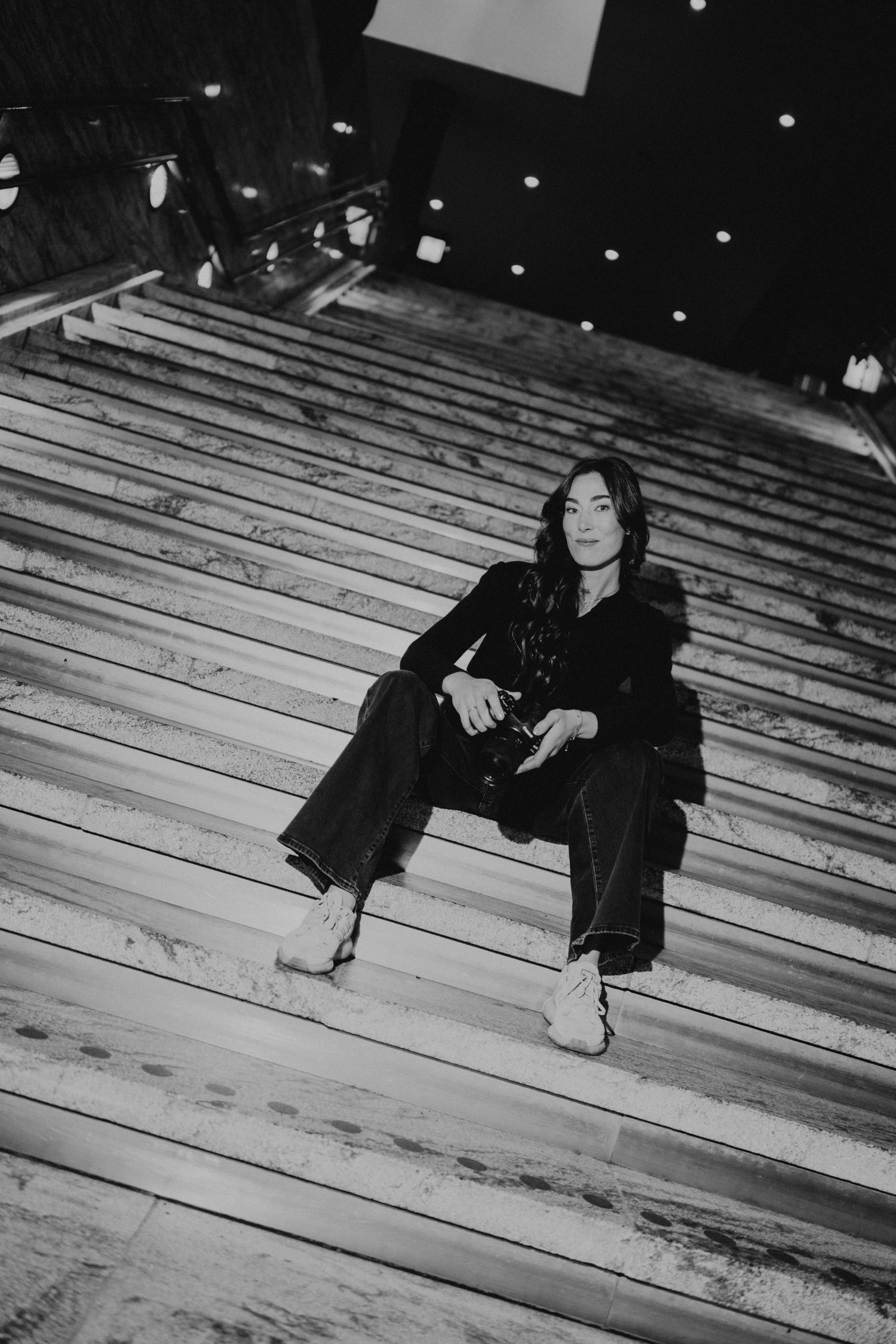 Black and white photo of person sitting on wooden steps at night.
