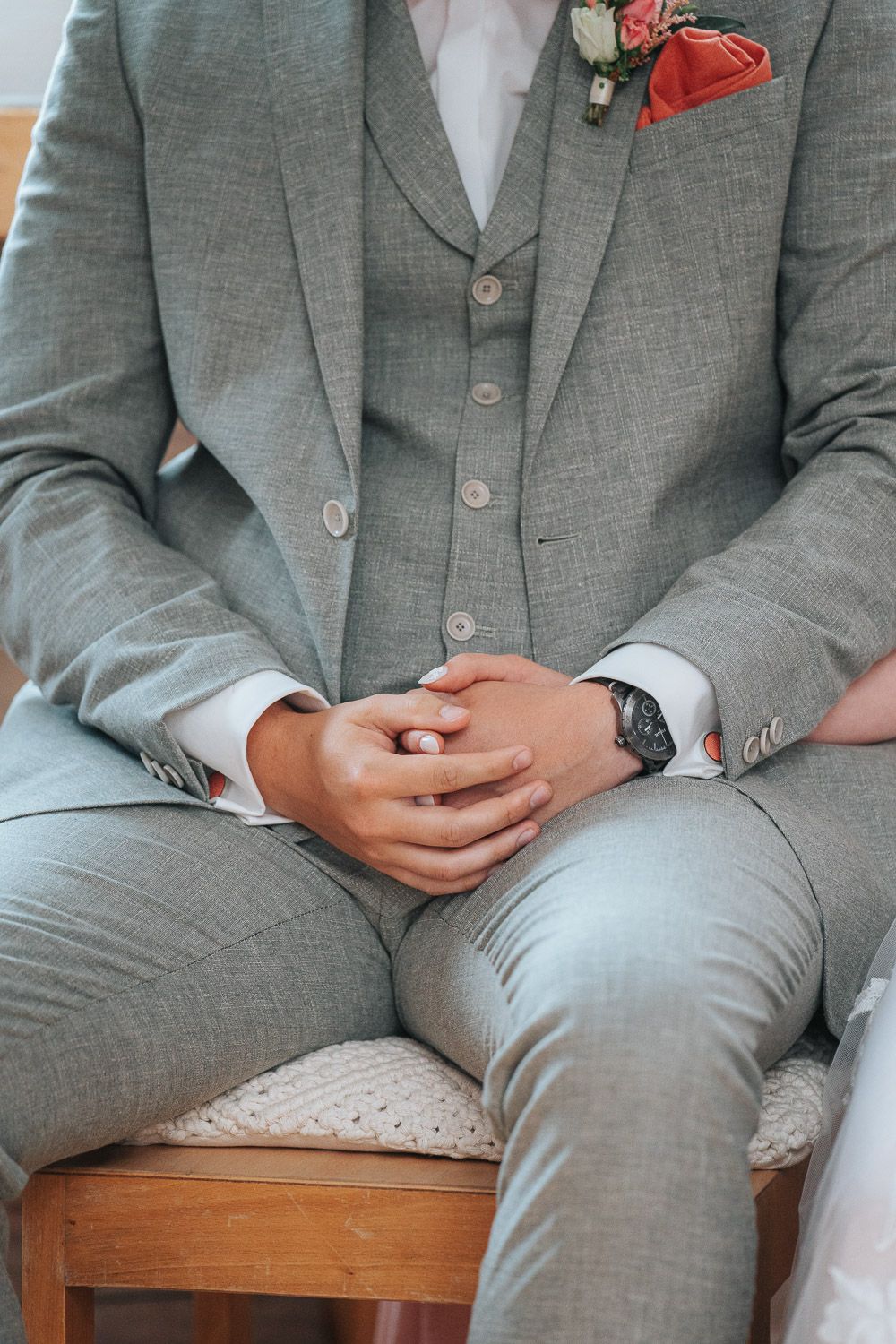 Four cropped views of someone wearing a light gray suit sitting on a wooden bench, showing details of the suit fabric.