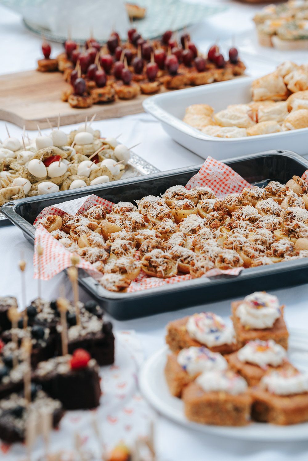 An assortment of homemade desserts and pastries displayed on platters and baking sheets at a party buffet table.