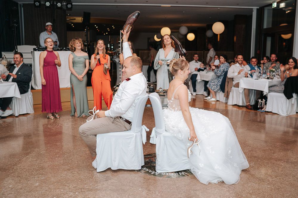 A large wedding reception dance floor with guests mingling and dancing in a brightly lit banquet hall.