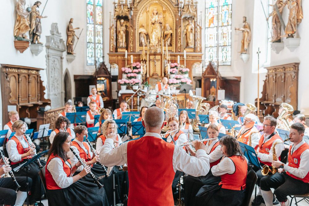 A group performs together in a historic church interior with decorative religious artwork and architecture.