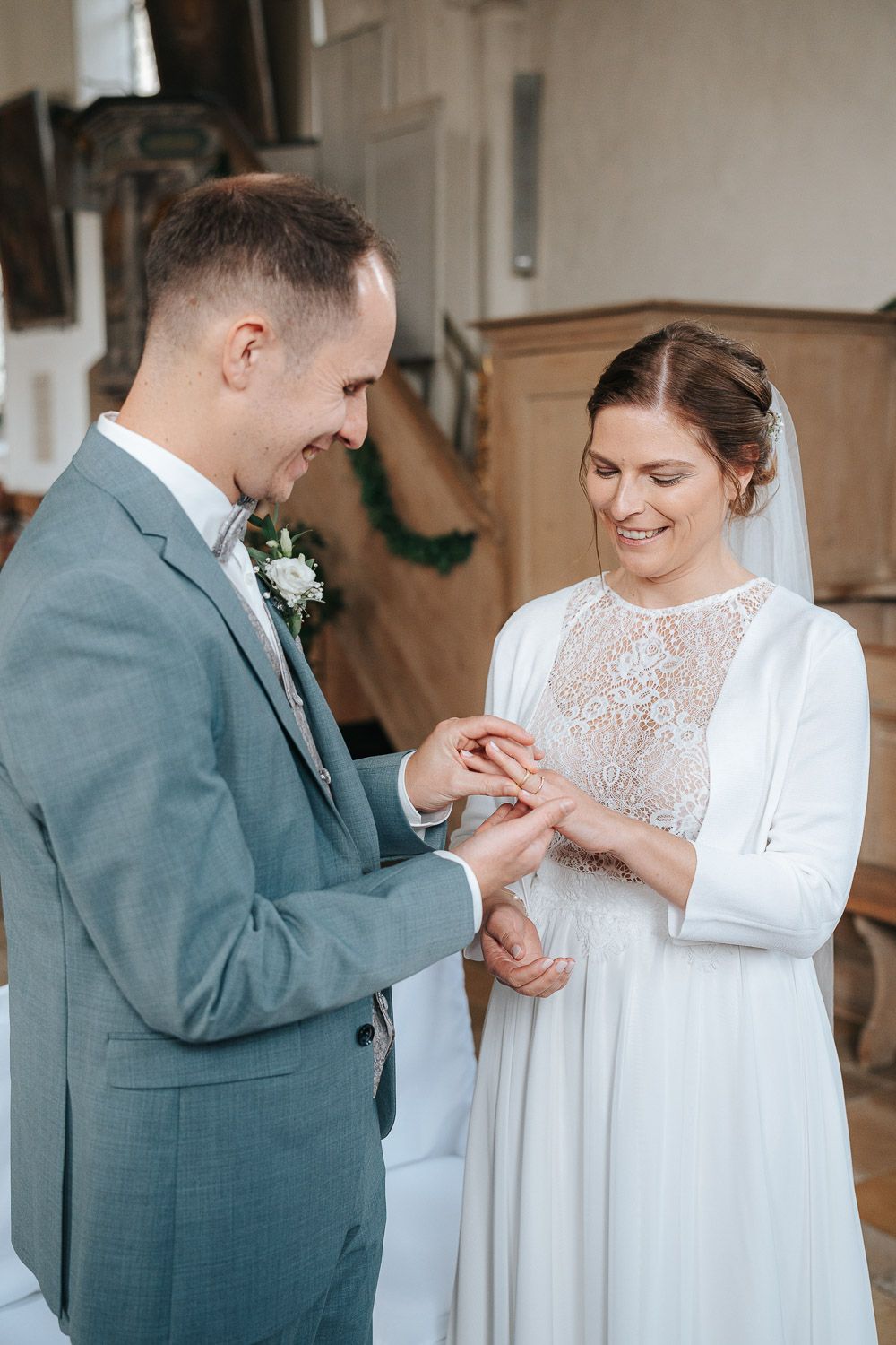 Romantic couple in their wedding attire share a tender moment as the groom gently touches the bride's hand during the ceremony.