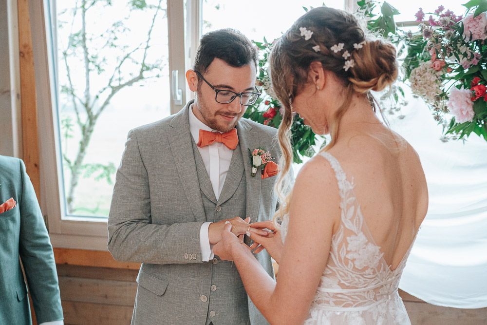 People sharing an intimate moment during a wedding ceremony in a rustic indoor venue by a window.