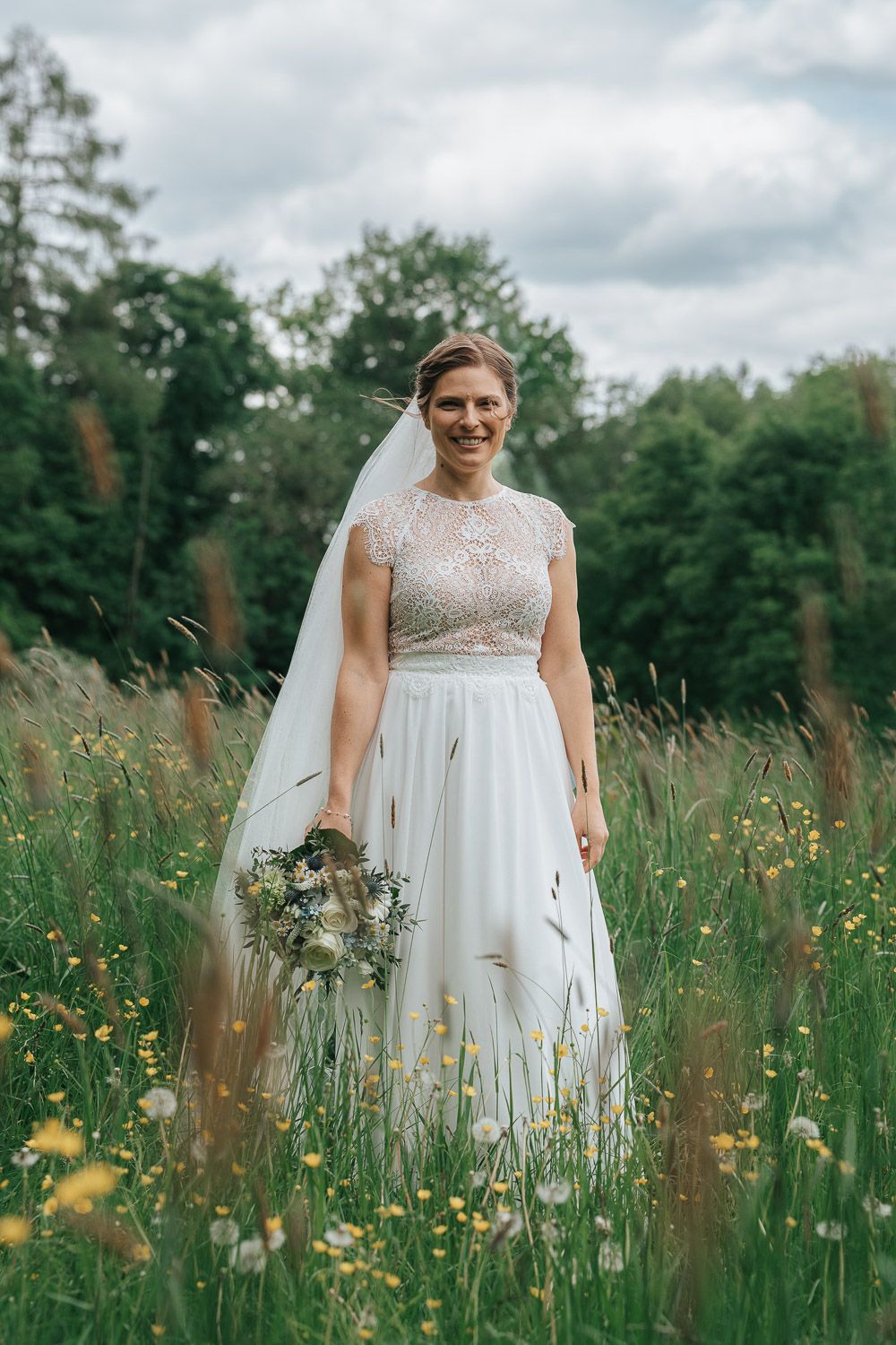 Beautiful wedding portrait in a wildflower meadow with a flowing white dress and delicate floral bouquet.