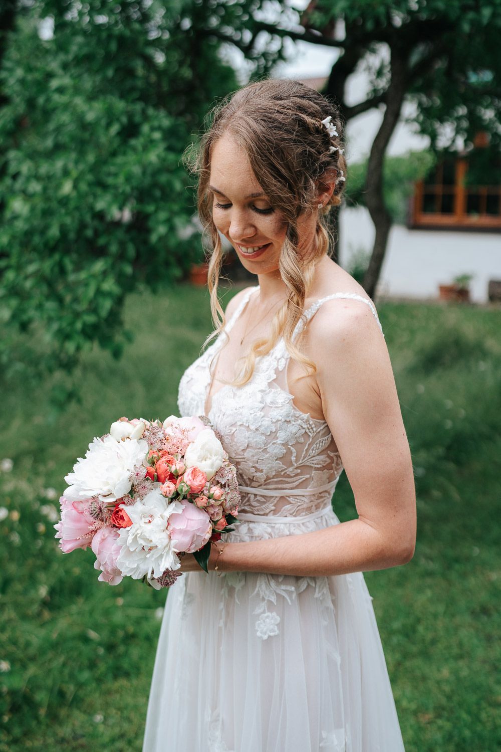 Elegant bridal portrait featuring delicate white and pink bouquet against garden backdrop with soft natural lighting.