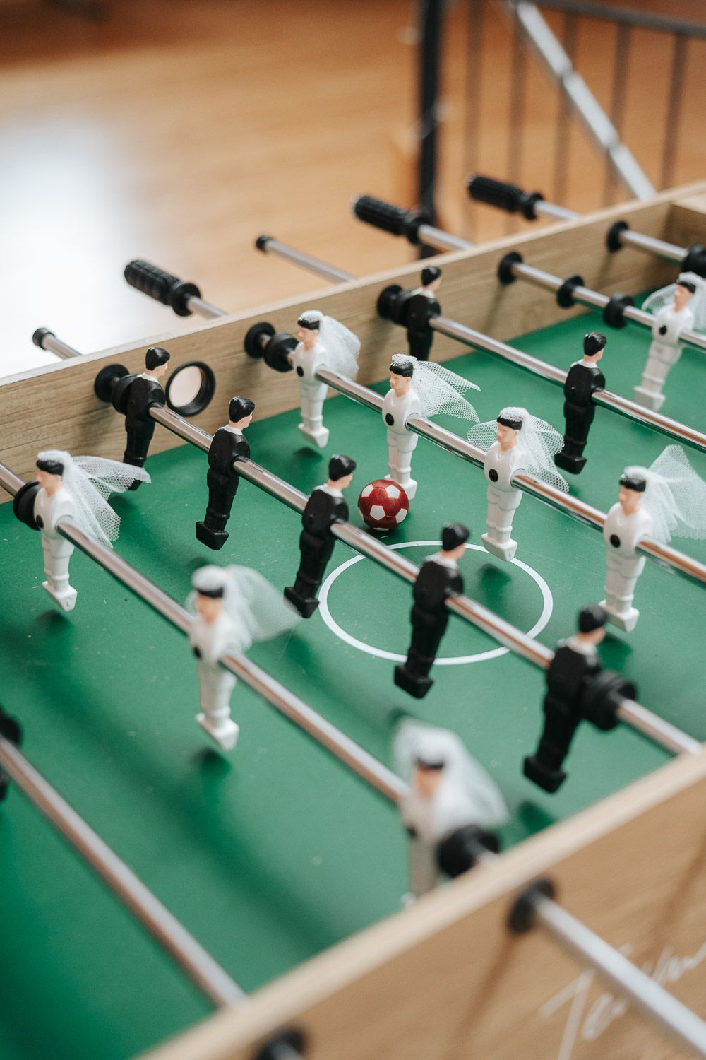 Close-up view of foosball table players and rods showing white and black figures on green playing surface.